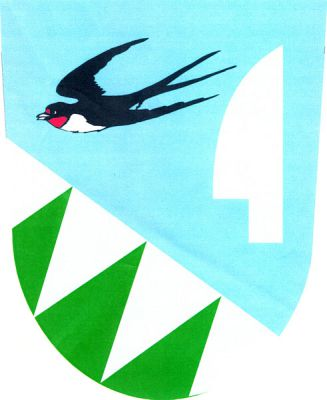 V modro-stříbrně kosmo sníženě děleném štítě nahoře letící vlaštovka přirozené barvy, provázená vlevo vztyčenou stříbrnou radlicí, dole tři šikmé zelené kužely. Znak Vlaštovičky